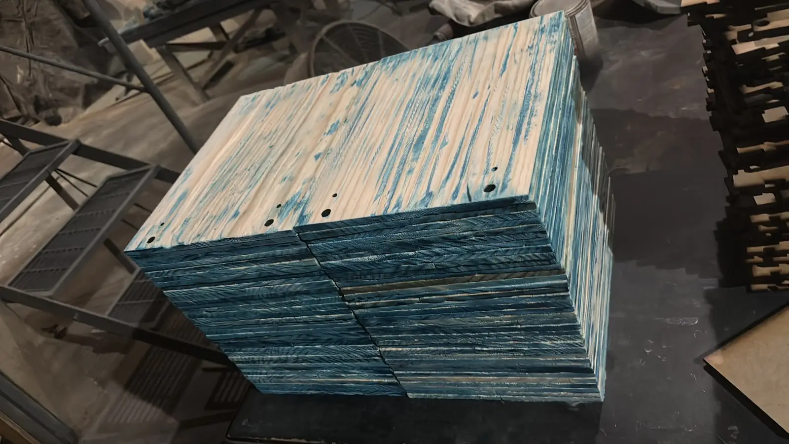 Tableros de madera teñidos de azul apilados sobre la mesa del taller