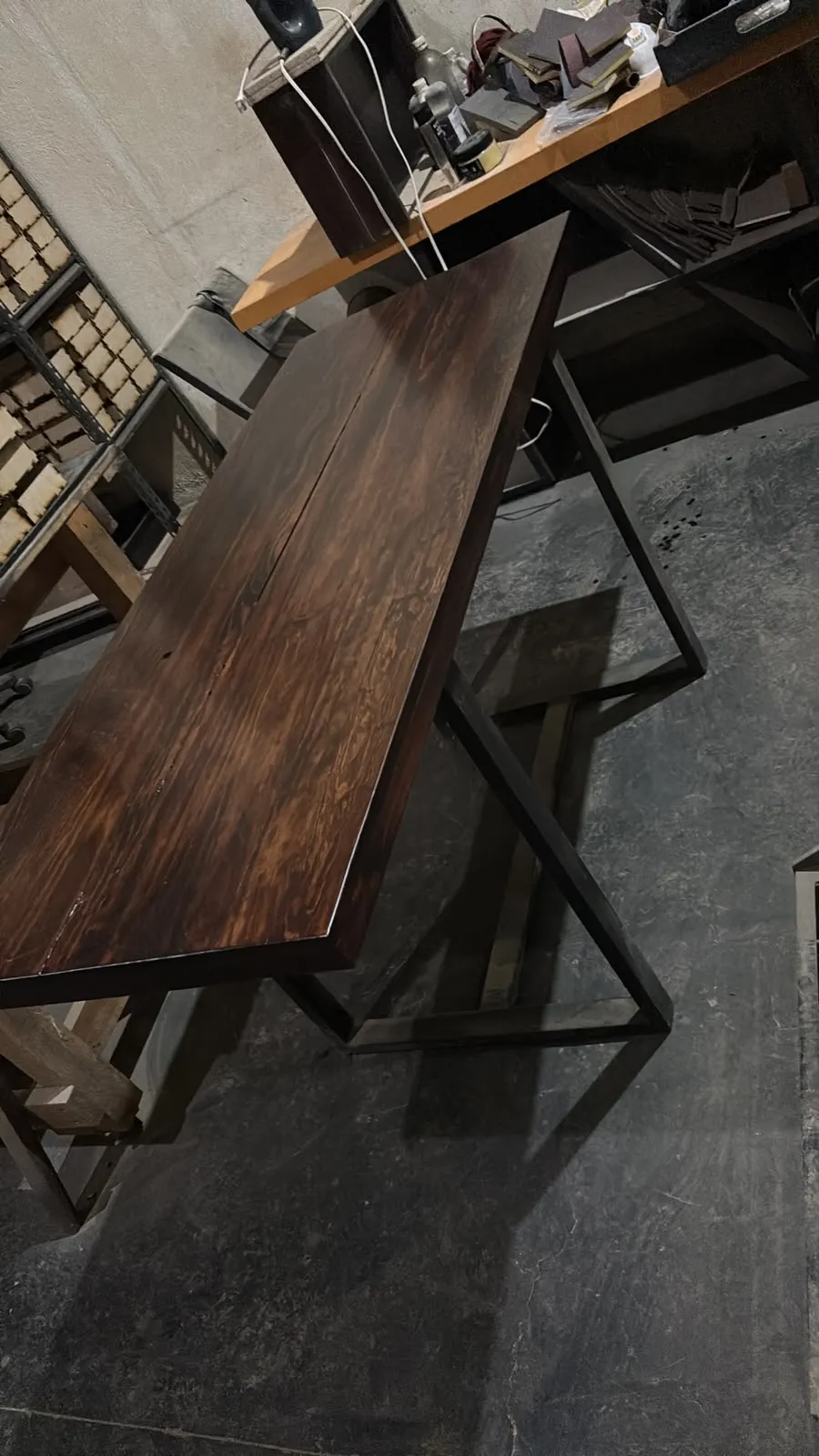 Mesa de madera oscura con estructura metálica negra dentro del taller