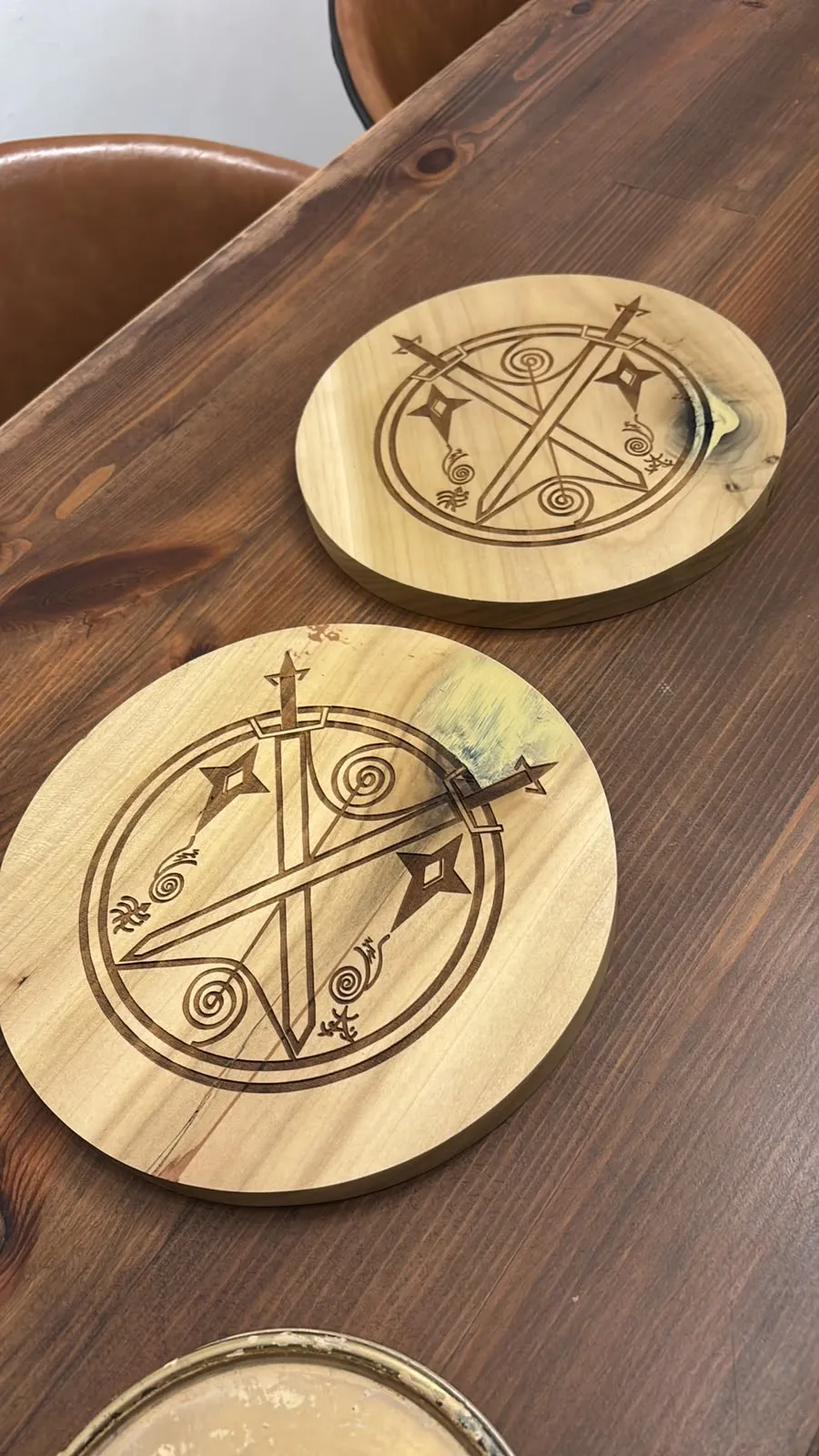 Posavasos redondos de madera clara con emblema grabado sobre una mesa