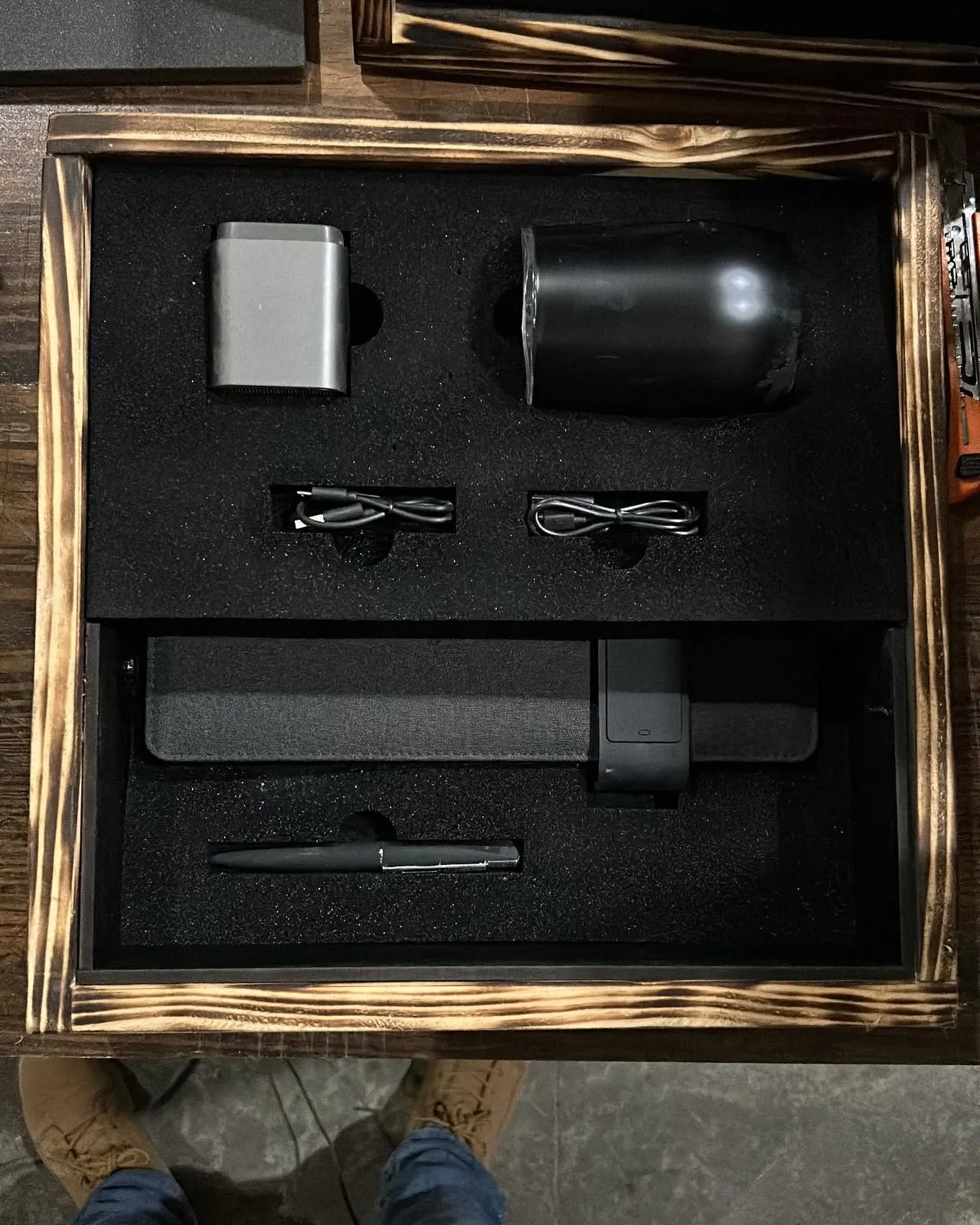 Caja de madera quemada abierta con interior de espuma troquelada a la medida de un kit tecnológico