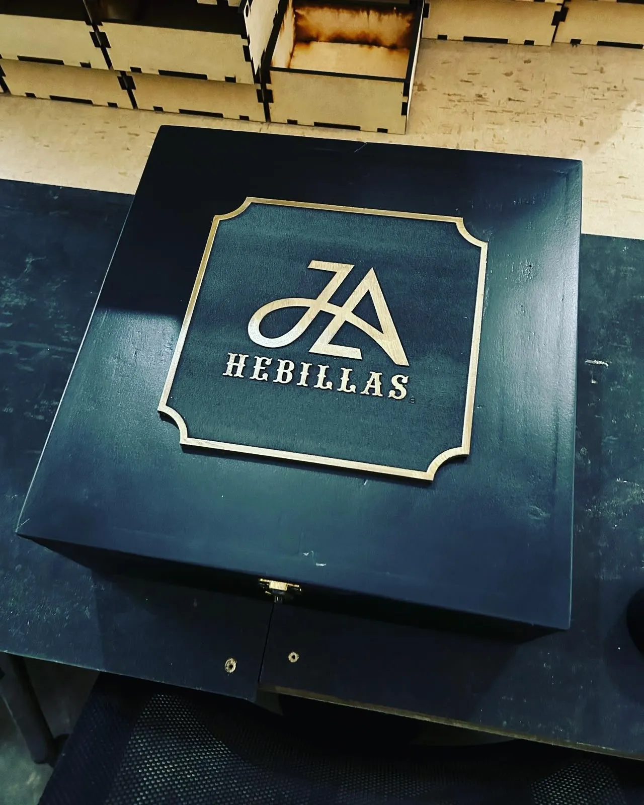 Caja de madera azul marino con logotipo en relieve y marco dorado