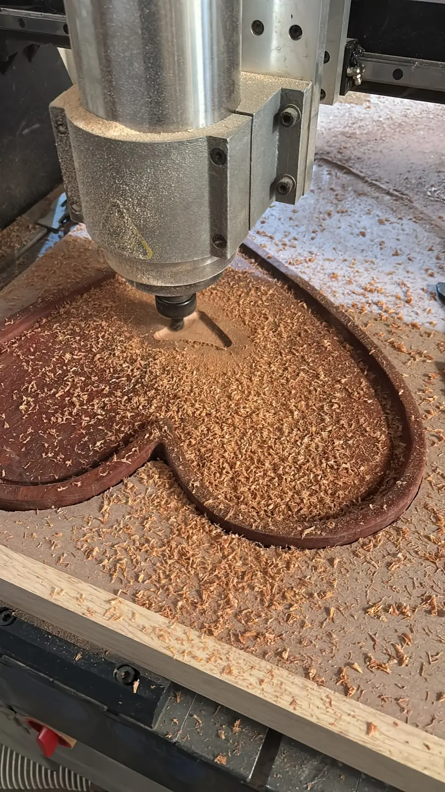 Router CNC desbastando la cavidad de una charola de madera en forma de corazón