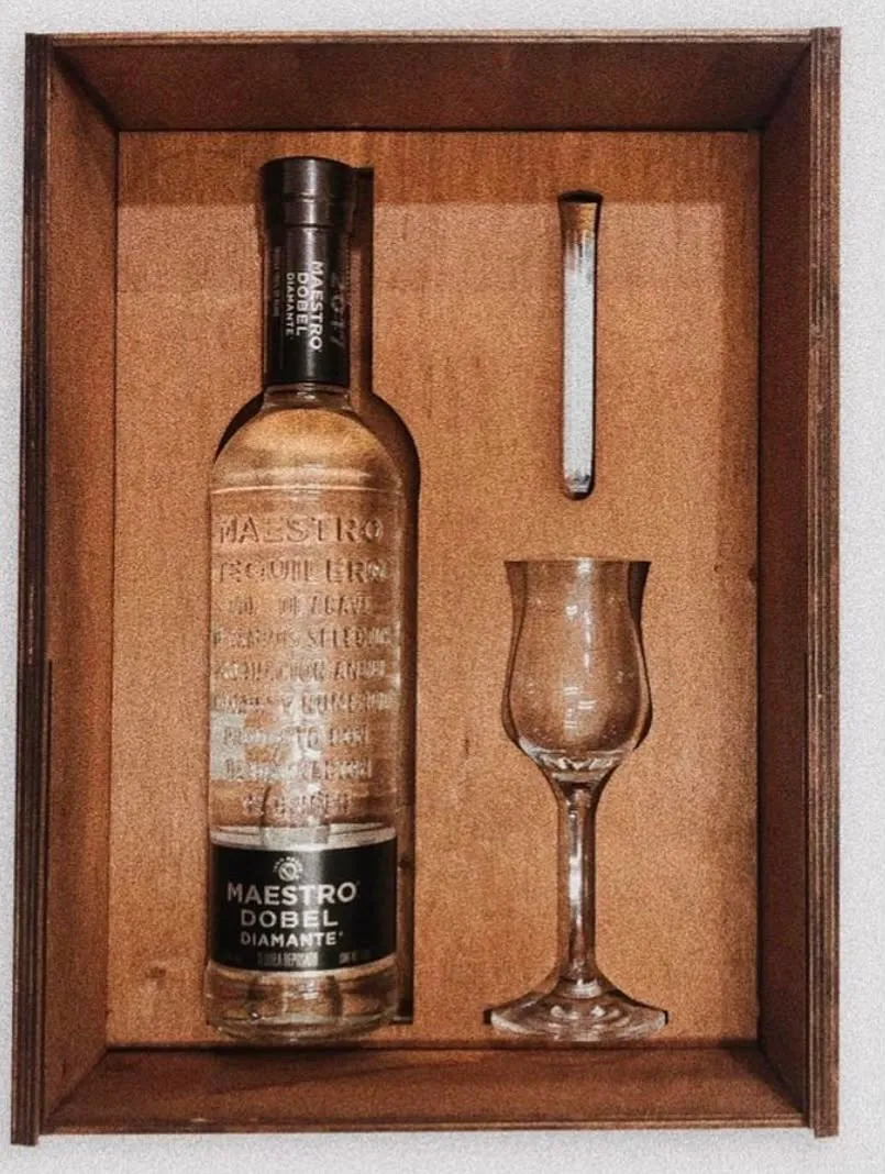 Estuche de madera terminado con una botella de tequila y una copa encajadas a la medida