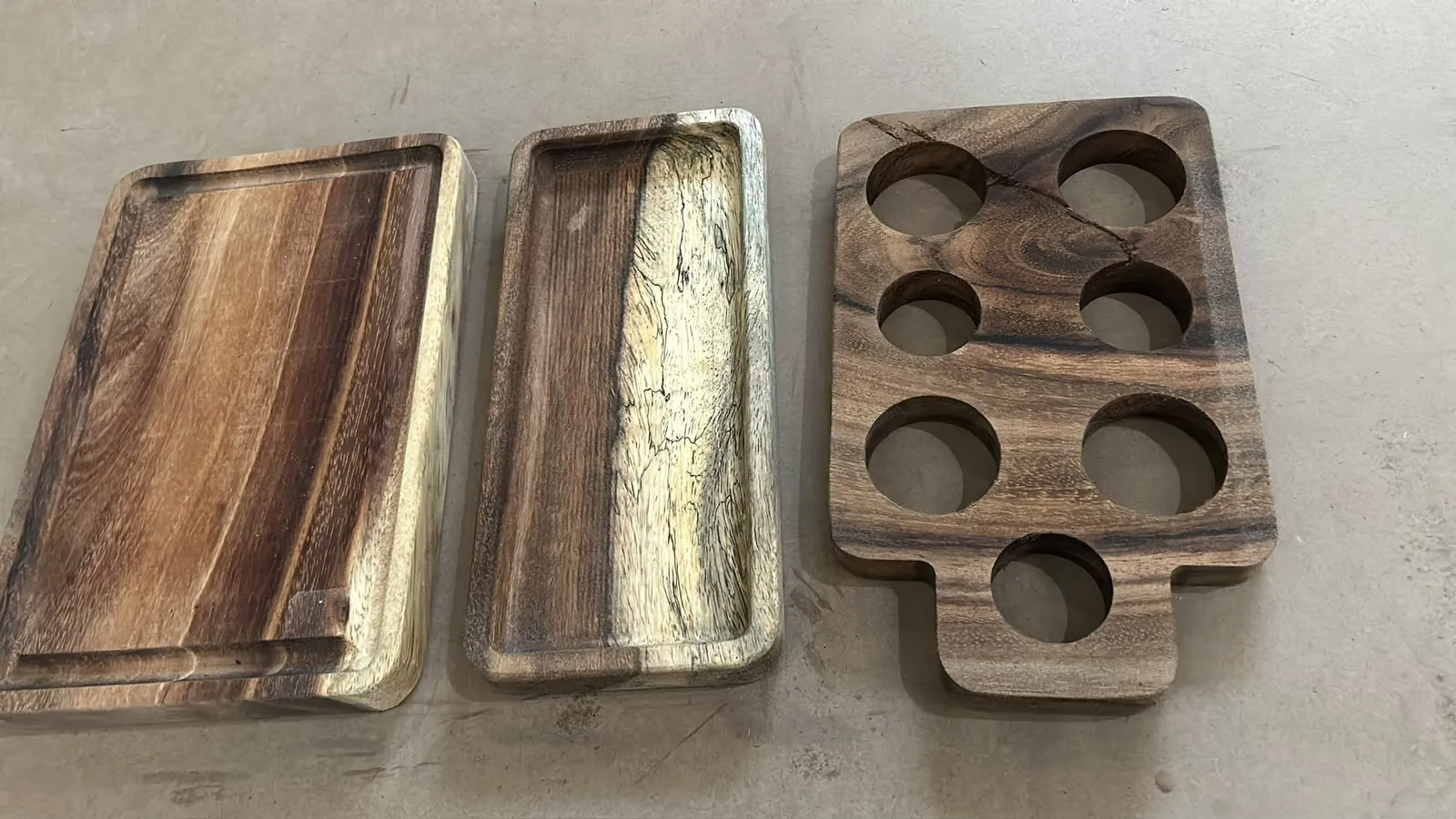 Charolas y base portavasos de madera terminadas sobre el piso del taller
