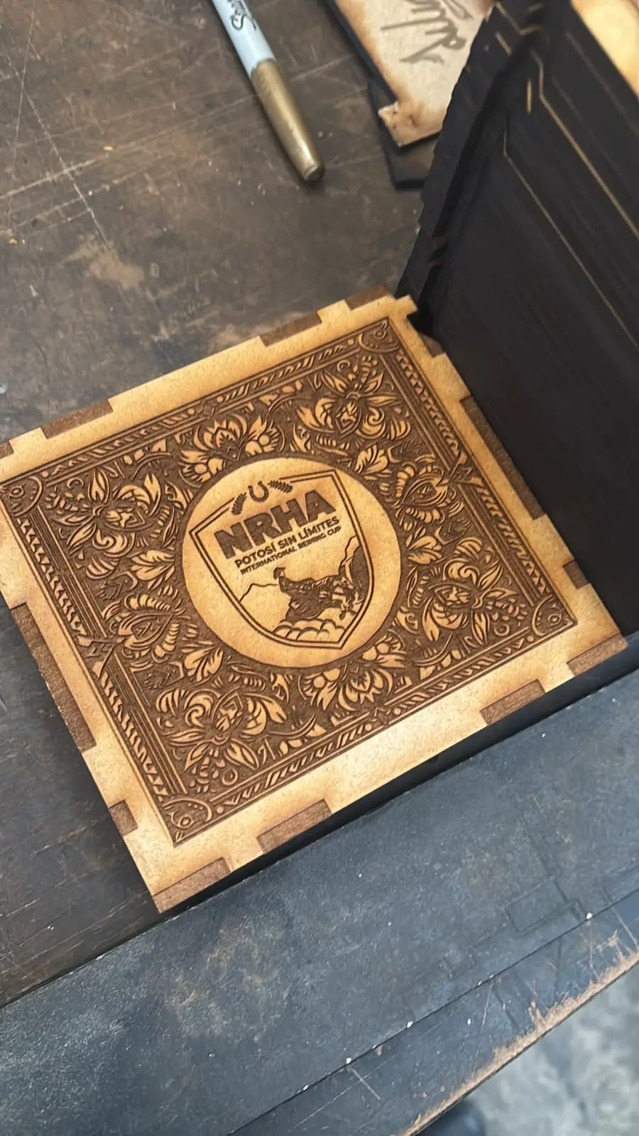 Caja de MDF con grabado láser de un logotipo rodeado de ornamento floral